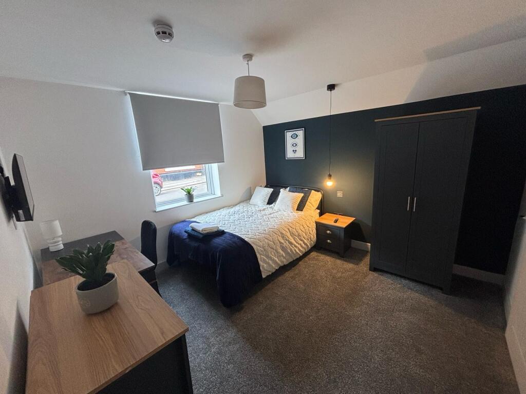 A cozy double bedroom featuring a stylish bed a...