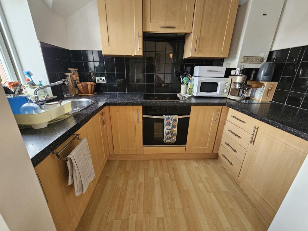 Modern kitchen with ample cabinetry, black tile...