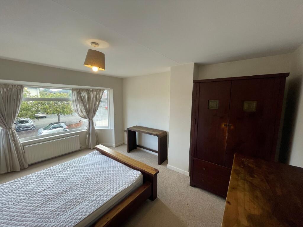 A bright and airy bedroom featuring a large win...