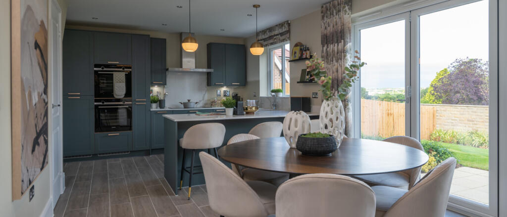 Modern open-plan kitchen and dining area with blue cabinets, beige chairs, and large sliding glass d