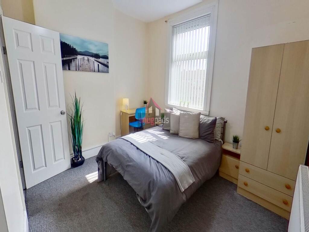 A well-lit bedroom featuring a comfortable doub...