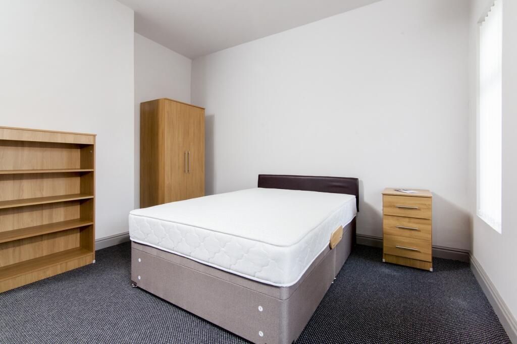 A spacious and tidy double bedroom featuring a ...