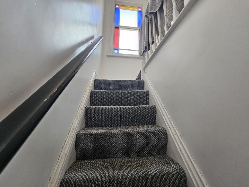 Carpeted staircase with clean white walls and a...