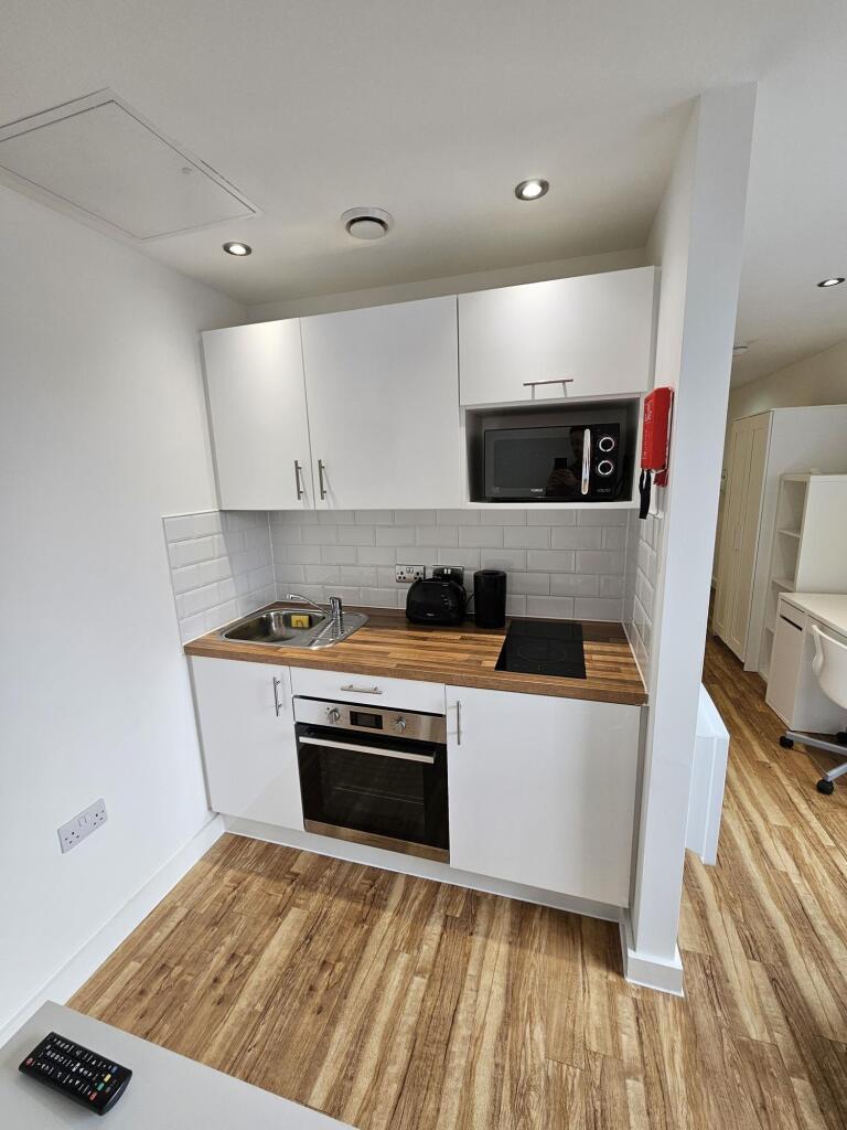 Compact, modern kitchen area featuring white ca...