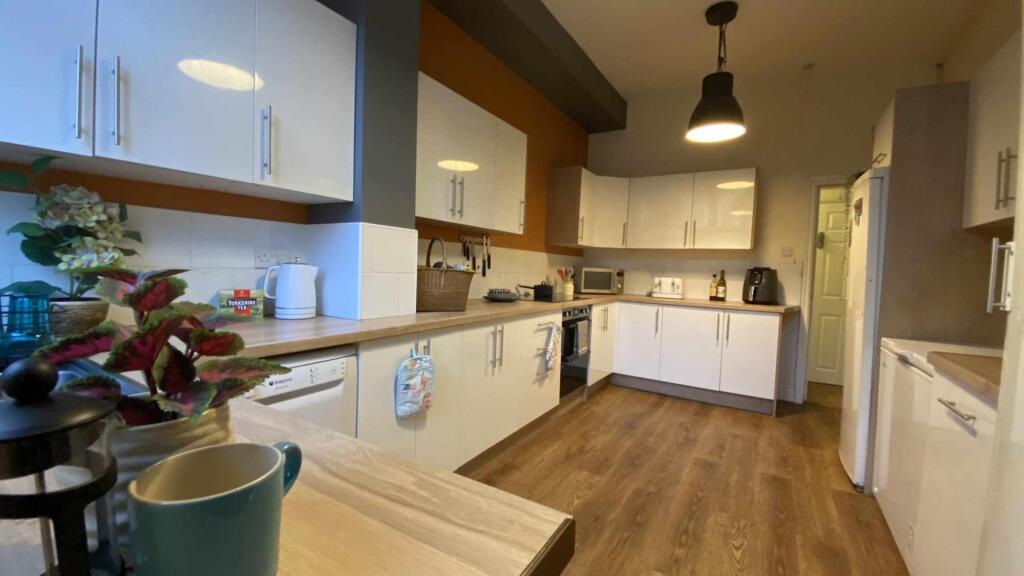 Bright, modern galley kitchen with white cabine...