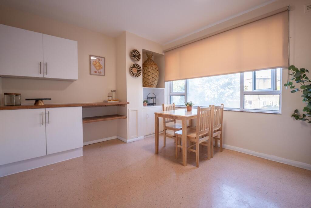 A bright kitchen area featuring a wooden dining...