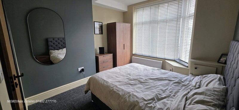 A cozy double bedroom featuring a large window ...