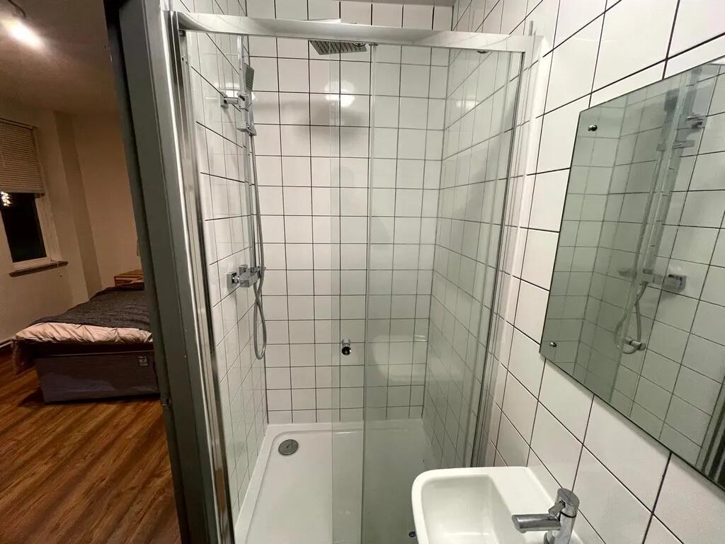 A modern ensuite bathroom featuring white tiled...