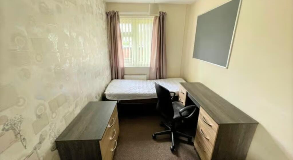 A tidy and well-kept single bedroom featuring a...