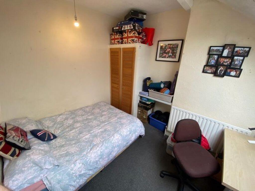 A cozy single bedroom with a neatly made bed, d...