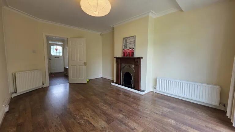 Bright living room with warm wooden floors, a c...