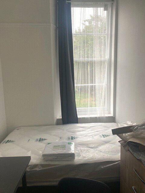 A simple, clean single bedroom with a large win...