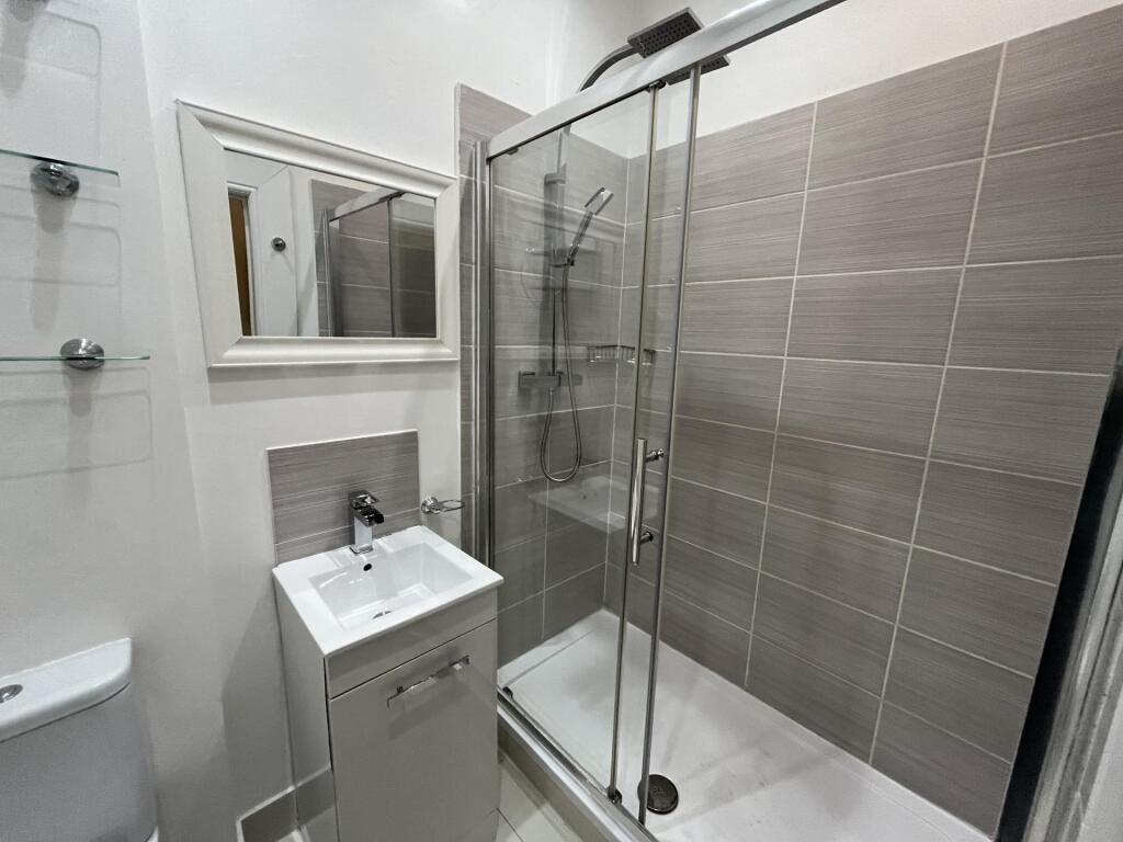 A modern bathroom featuring a glass-enclosed sh...