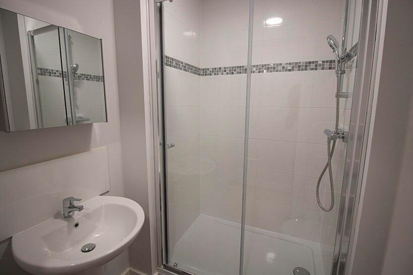 A modern bathroom suite featuring a glass-enclo...
