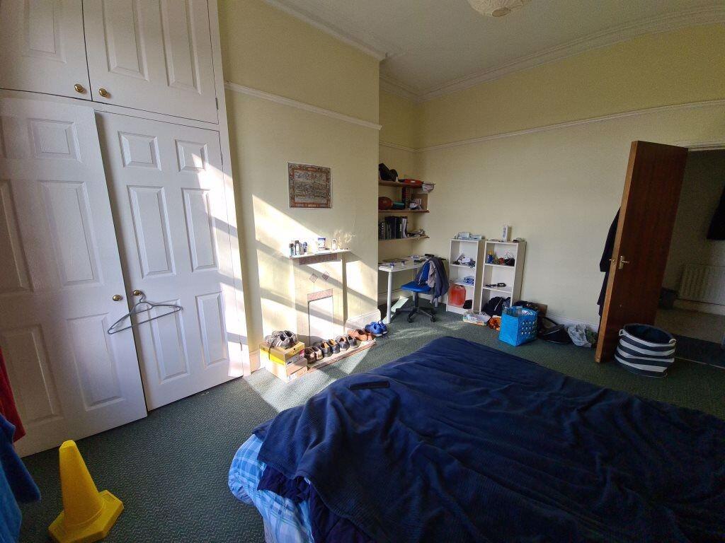 A tidy bedroom with a large bed, a window provi...