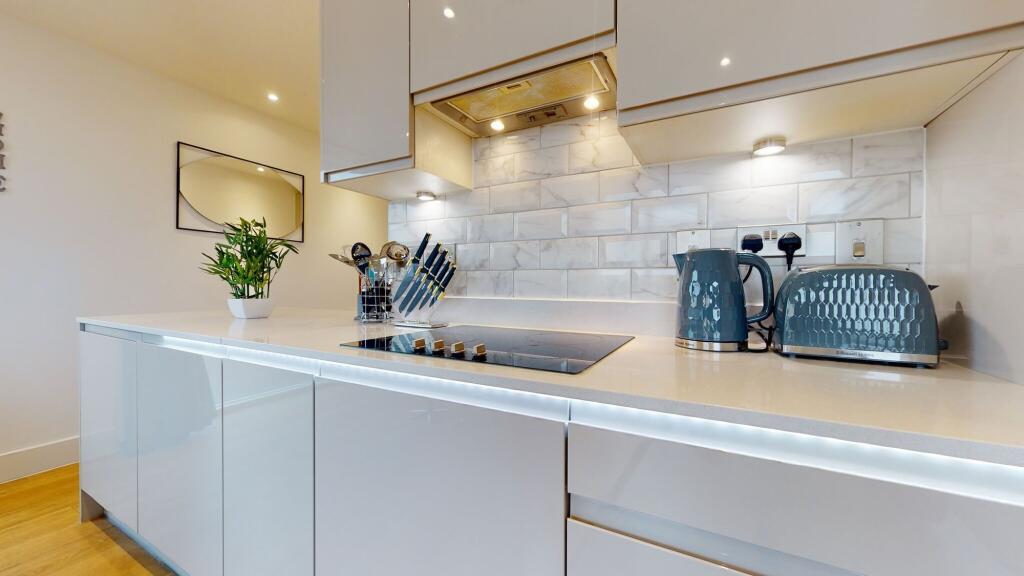 A sleek, modern kitchen featuring glossy white ...