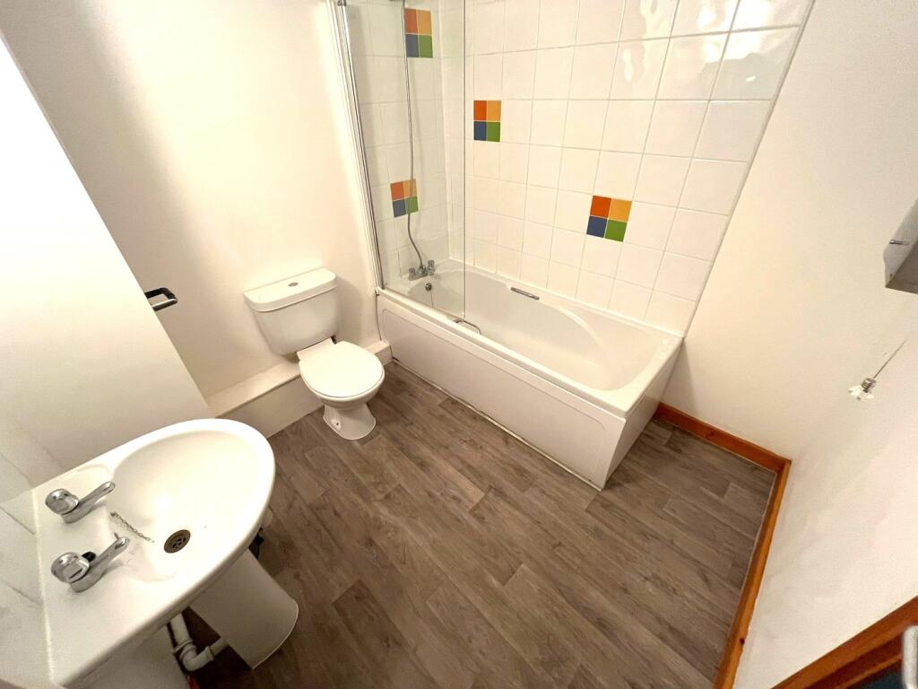 A bright and tidy bathroom featuring a bath and...