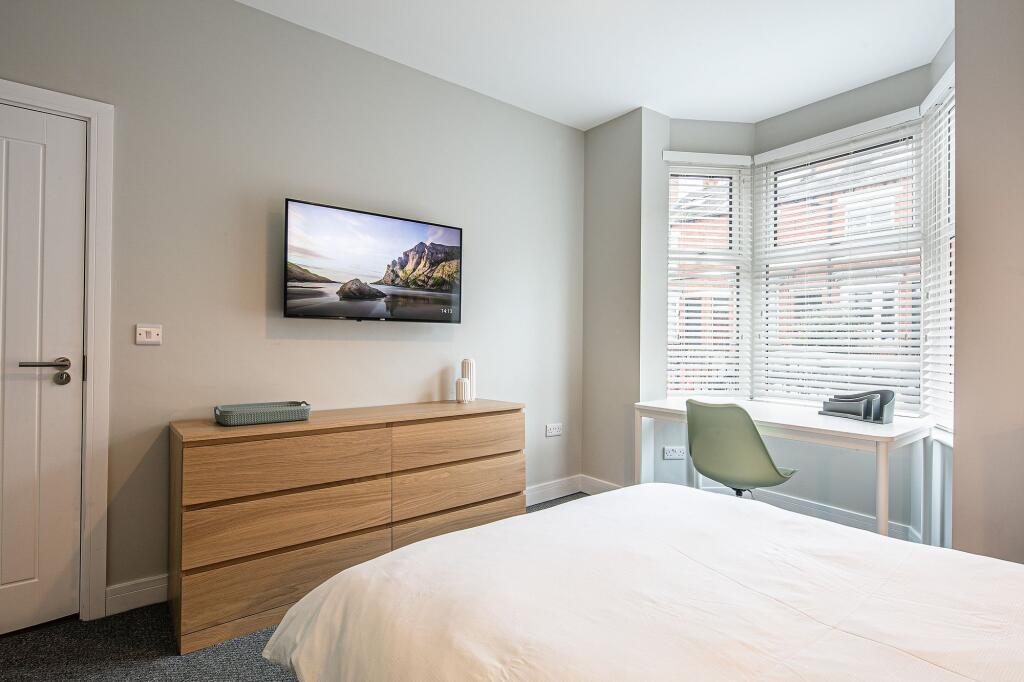 Bright and modern bedroom featuring a large win...