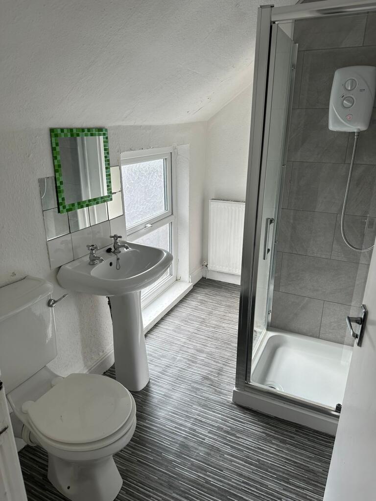 A bright, clean bathroom featuring a shower enc...