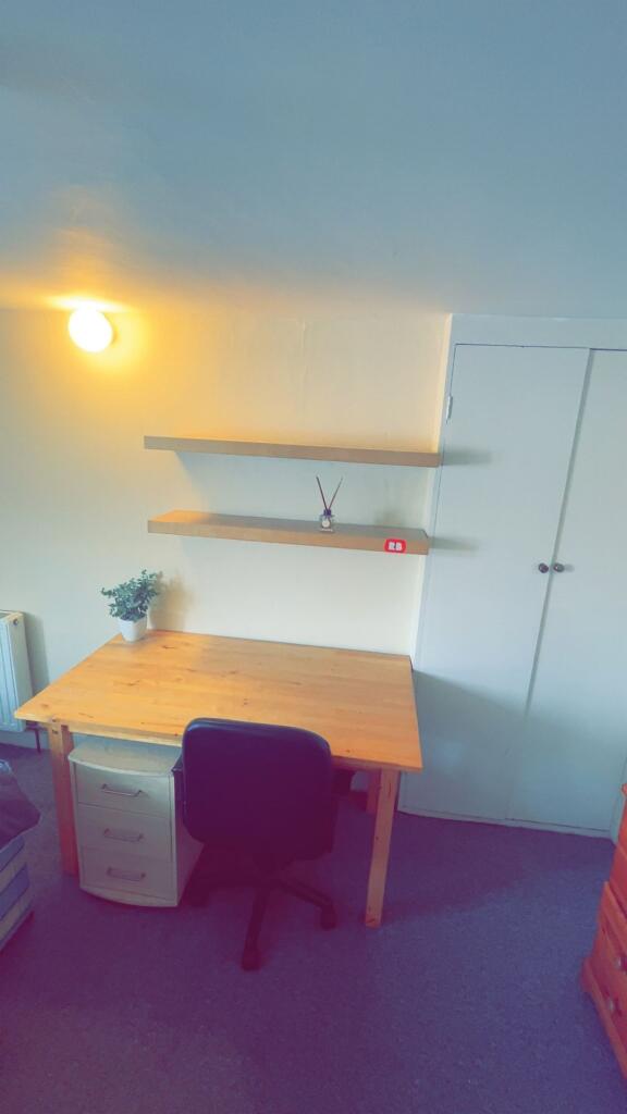 A well-lit, tidy study corner featuring a woode...