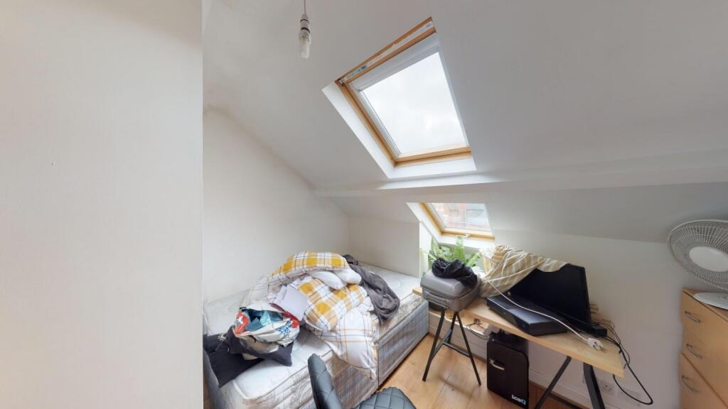 Bright attic room featuring a skylight window t...