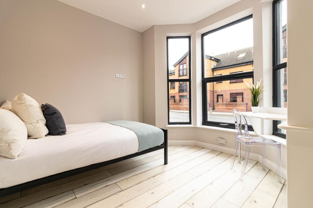 Bright, modern bedroom with large bay windows p...