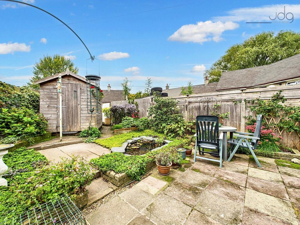 Spacious Flagged Garden with Mature Shrubs and Pond