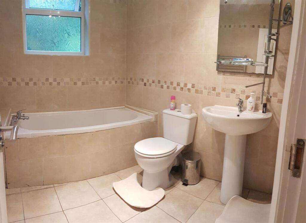 Bright, tiled bathroom featuring a corner bath,...