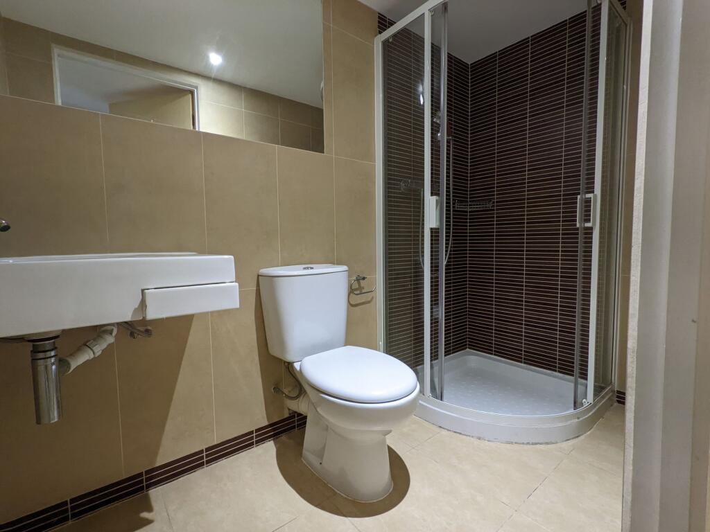Modern tiled bathroom with a corner glass showe...
