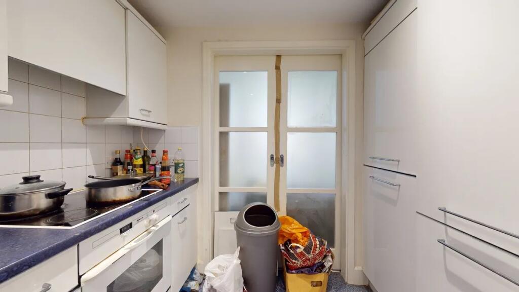 Compact kitchen space featuring white cabinetry...