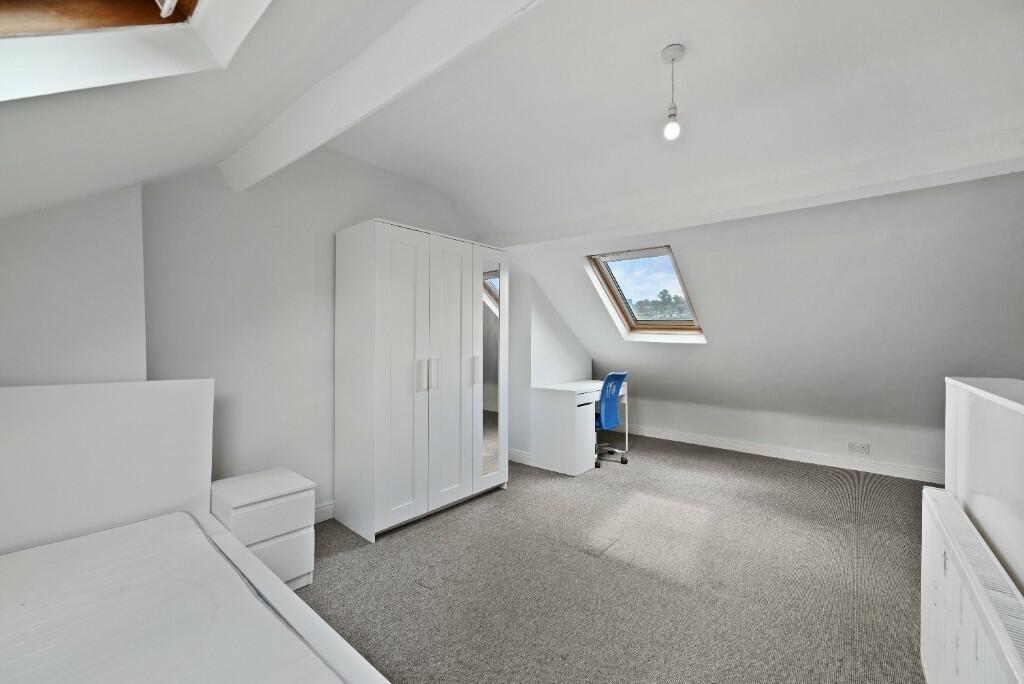 Bright and airy attic bedroom featuring slanted...