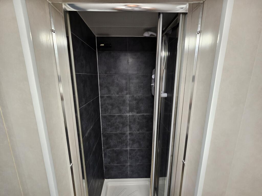 A modern shower space with sleek dark gray tile...