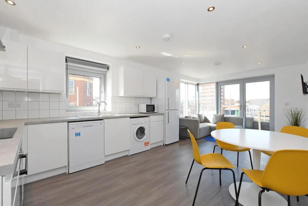A modern and bright kitchen and dining area fea...