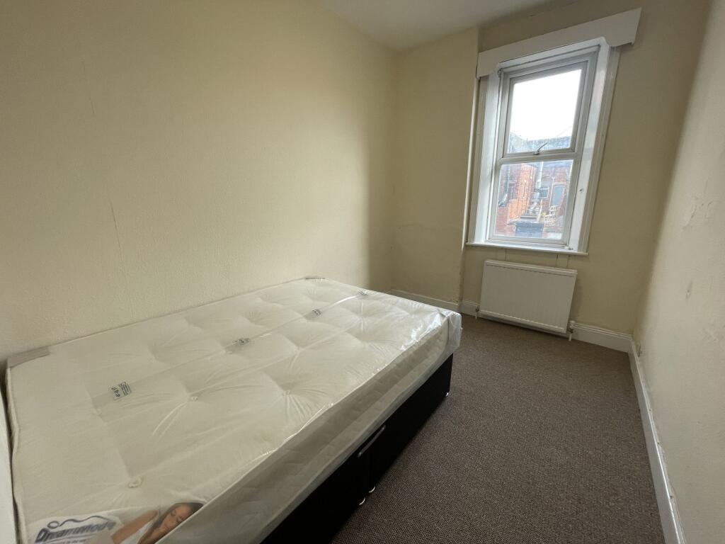 A simple single bedroom featuring a bed with a ...