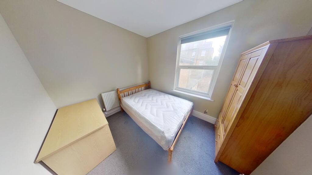 A simple and tidy single bedroom featuring a wo...
