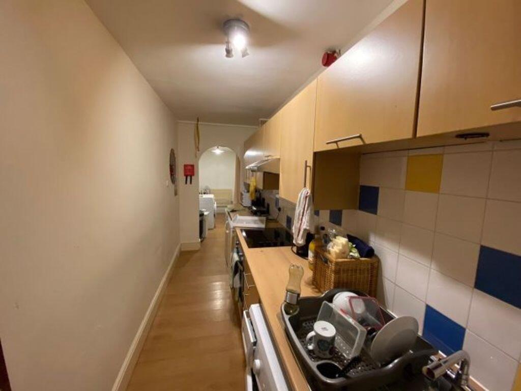 A narrow kitchen space featuring wooden cabinet...