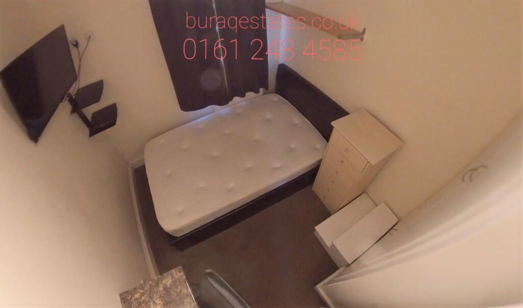 Compact bedroom with a single bed, fitted stora...