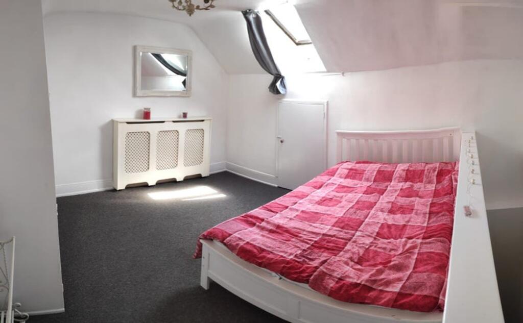 A bright double bedroom with a red checkered bl...