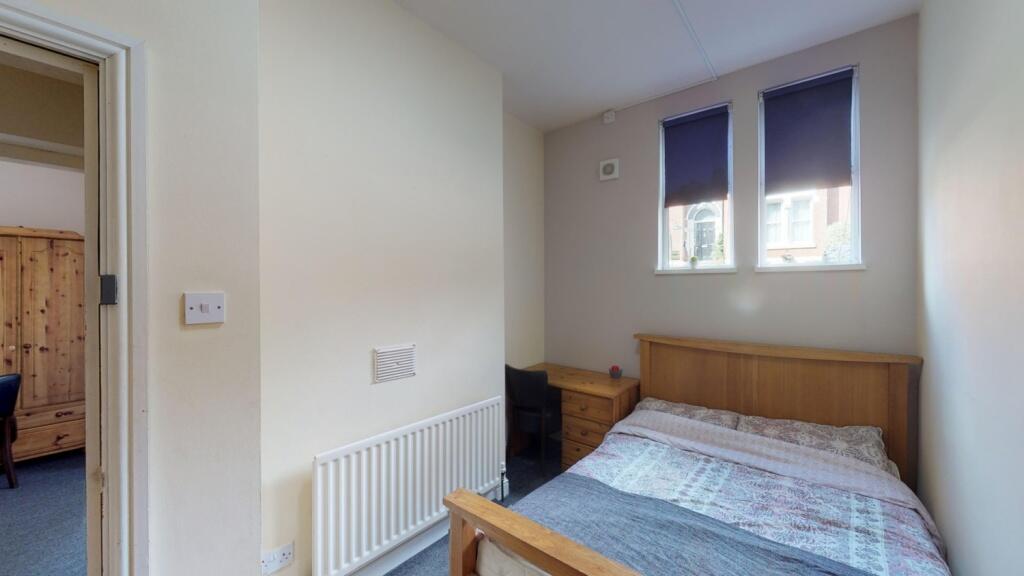 Cozy single bedroom featuring a wooden bed fram...