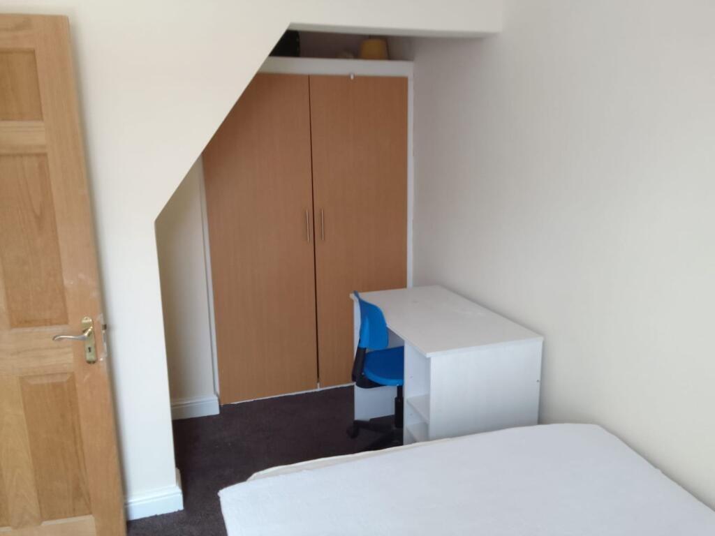 A cozy single bedroom featuring a clean, white ...