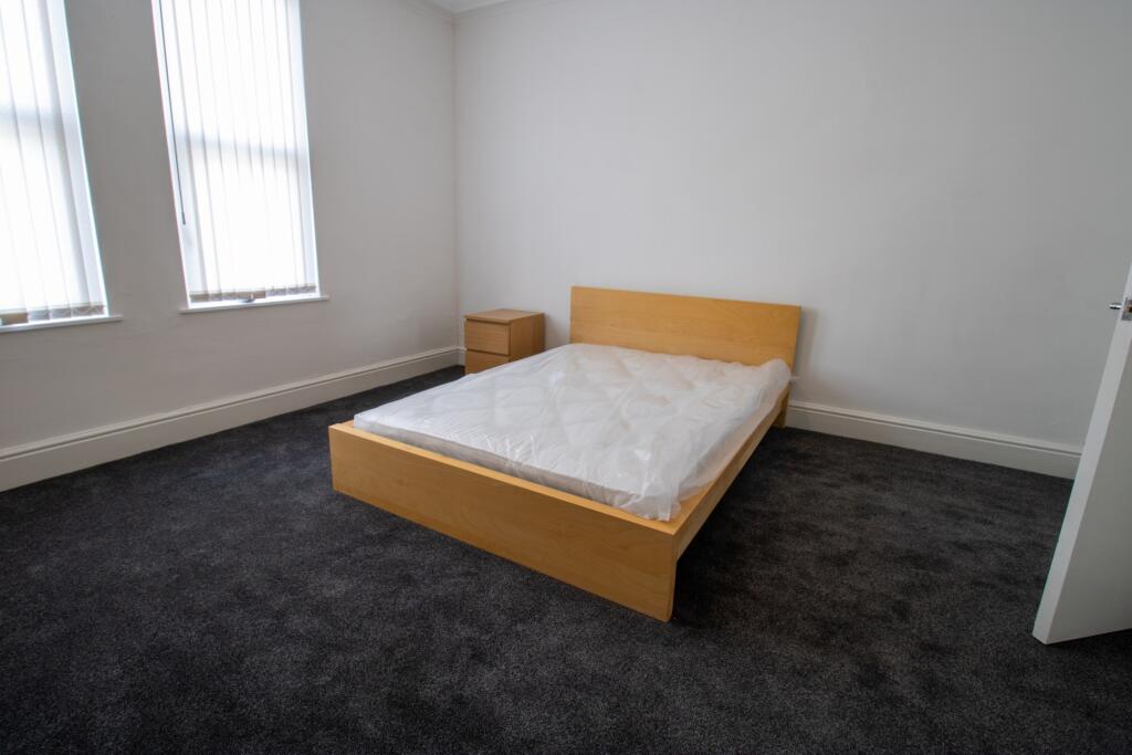 A clean and bright single bedroom featuring a w...
