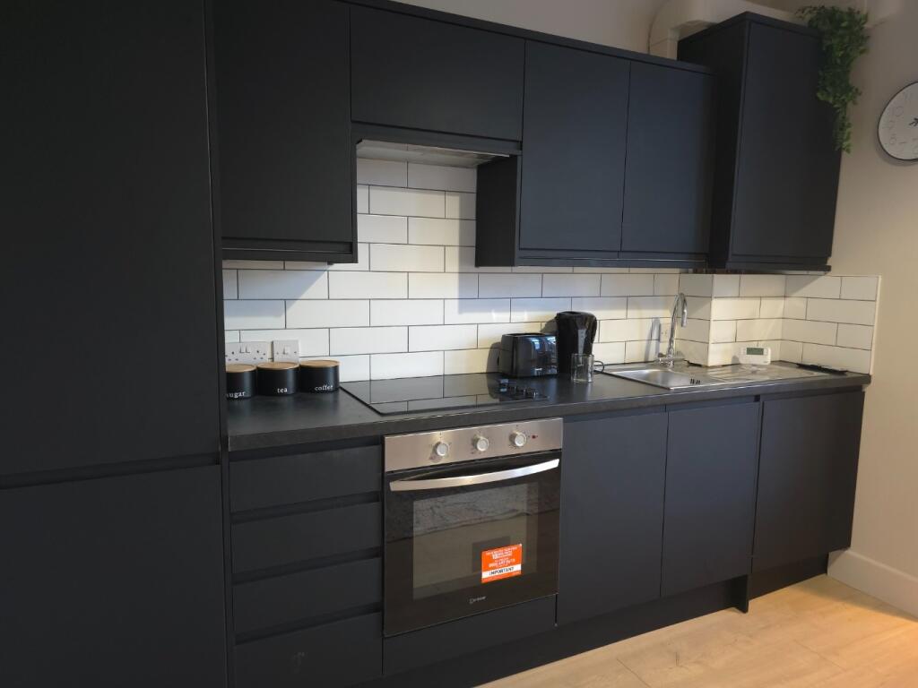 Modern fitted kitchen with dark cabinetry, inte...