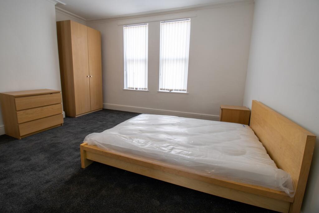A tidy and well-lit bedroom featuring a simple ...
