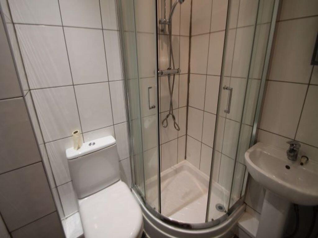 Bright, tiled bathroom with a corner shower enc...