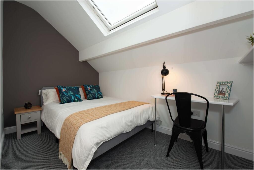 A bright and tidy bedroom featuring a comfortab...