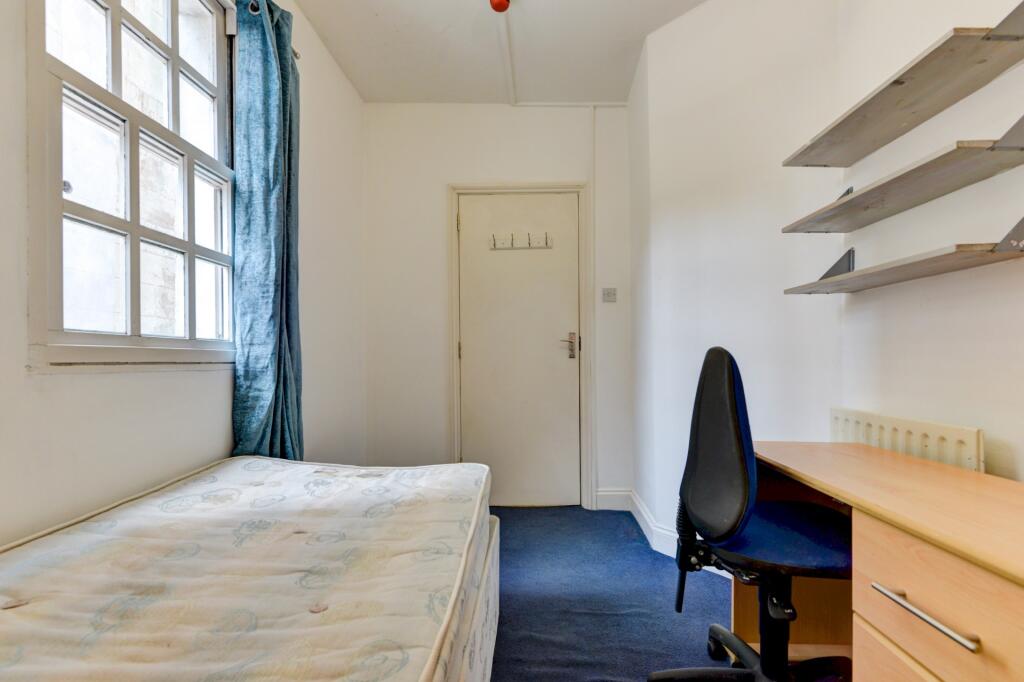 Bright single bedroom featuring a large window ...