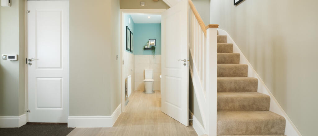 Interior view of a modern home with a staircase, doorways, and a small bathroom at the end, decorate