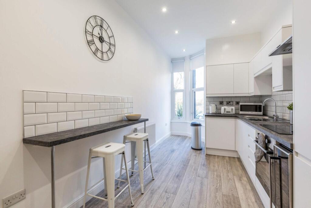 Bright modern galley kitchen with wood-effect f...