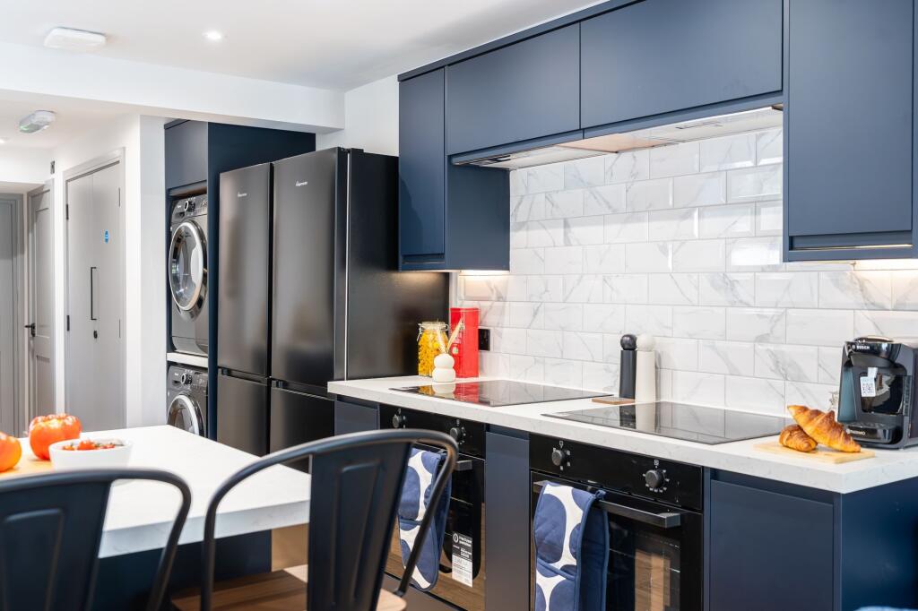 Modern kitchen featuring sleek navy blue cabine...