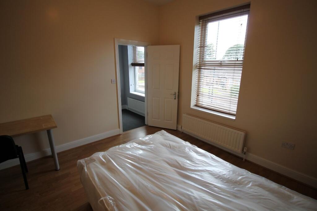 A tidy double bedroom featuring a large window ...